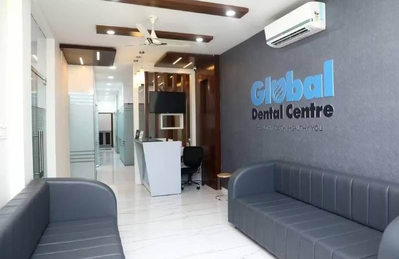 The reception area of Global Dental Centre, showcasing a modern, stylish space with gray seating, the clinic's logo on the wall, and a clean, professional environment.